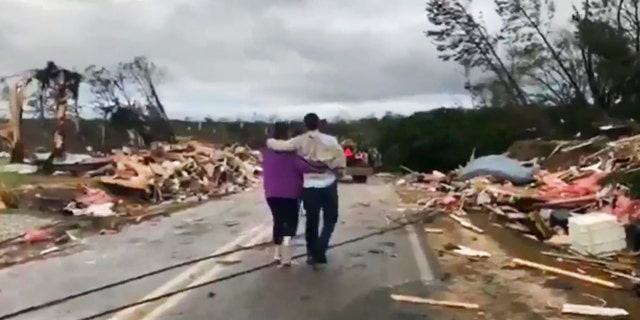 People walk amid debris in Lee County, Ala., after a tornado struck in the area Sunday, March 3, 2019.