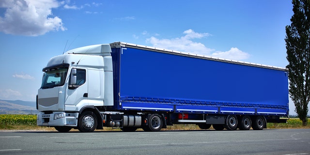 White semi truck and blue trailer on the road.