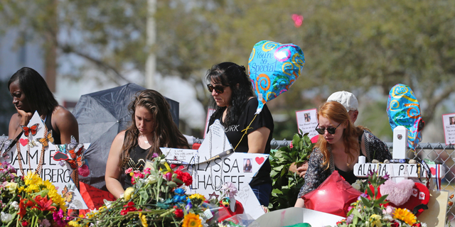In this Feb. 25, 2018, file photo, mourners bring flowers as they pay tribute at a memorial for the victims of the shooting at Marjory Stoneman Douglas High School, in Parkland, Fla. (David Santiago/Miami Herald via AP, File)