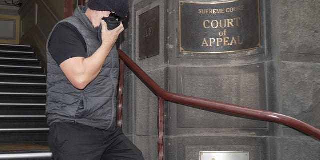 Workplace bullying claimant David Hingst covers his face as he leaves the Court of Appeal in Melbourne, Australia Friday, March 29, 2019. The Australian appeals court on Friday dismissed a bullying case brought by the engineer Hingst who accused his former supervisor of repeatedly breaking wind toward him.