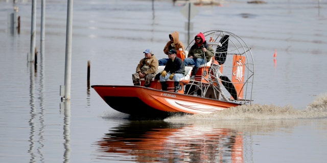 Gabe Schmidt, owner of Liquid Trucking, back right, travels by air boat with Glenn Wyles, top left, Mitch Snyder, bottom right, and Juan Jacobo, bottom left, as they survey damage from the flood waters of the Platte River, in Plattsmouth, Neb., Sunday, March 17, 2019. (AP Photo/Nati Harnik)