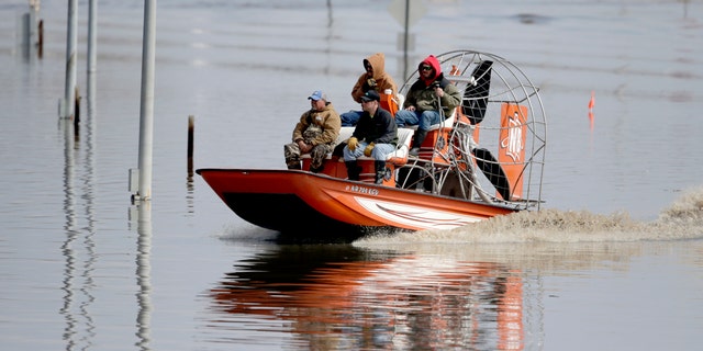 Gabe Schmidt, owners of Liquid Trucking, behind right, travels by atmosphere vessel with Glenn Wyles, tip left, Mitch Snyder, bottom right, and Juan Jacobo, bottom left, as they consult repairs from a inundate waters of a Platte River, in Plattsmouth, Neb., Sunday, Mar 17, 2019. (AP Photo/Nati Harnik)