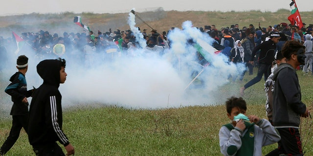 Protesters run for cover from teargas fired by Israeli troops near fence of Gaza Strip border with Israel, marking first anniversary of Gaza border protests east of Gaza City, Saturday, March 30, 2019. (AP Photo/Adel Hana)