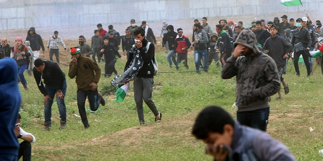 Protesters marking the first anniversary of Gaza border demonstrations run from tear-gas fired by Israeli troops near a fence on the border with Israel on Saturday, March 30, 2019. Tens of thousands of Palestinians protested. 