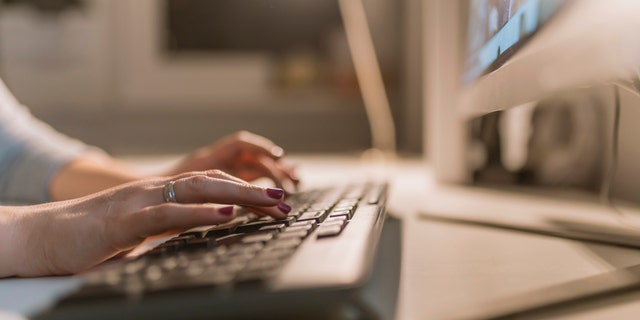 Photo of businesswomen working at office with monitor computer, young hipster manager typing on keyboard, closeup finger female hands texting message, work process concept in work space.