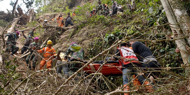Rescuers carry a survivor of the collapsed mine on a stretcher through a steep terrain.