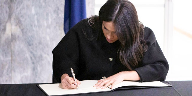 Britain's Meghan Duchess of Sussex signs the book of condolence, with Prince Harry, during a visit to the New Zealand High Commission in London, Tuesday March 19, 2019. The royal couple visited New Zealand Commission following the Mosque terrorist shootings last week. (Ian Vogler/pool via AP)