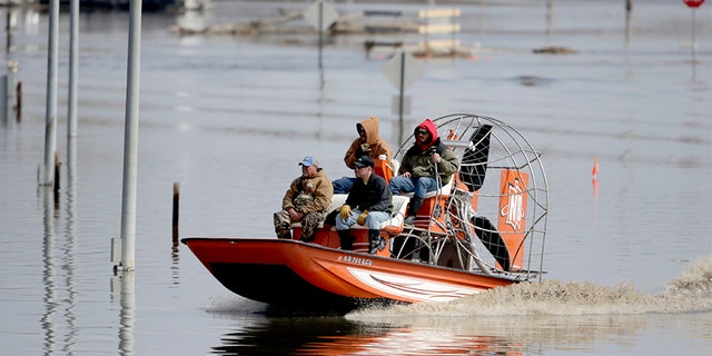 Gabe Schmidt, owner of Liquid Trucking, back right, travels by air boat with Glenn Wyles, top left, Mitch Snyder, bottom right, and Juan Jacobo, bottom left, as they survey damage from the flood waters of the Platte River, in Plattsmouth, Neb., on Sunday.