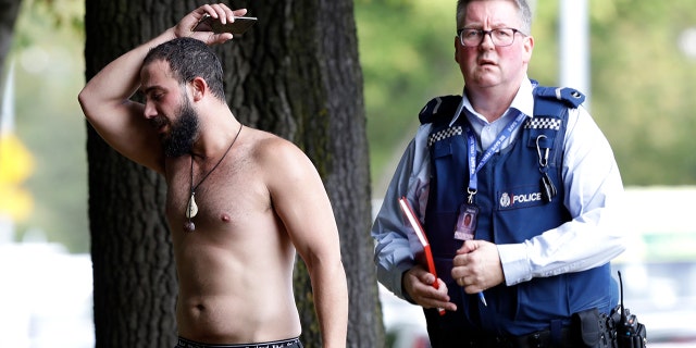 A police officer escorts a man away from a mosque in central Christchurch, New Zealand, Friday, March 15, 2019. (AP Photo/Mark Baker)
