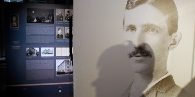 A shadow of Milica Kesler, curator and archivist is cast onto a poster of Nikola Tesla at the Nikola Tesla museum in Belgrade, Serbia, Thursday, March 7, 2019. A private culture society in Serbia has made public two letters written by Serb-American inventor and electricity pioneer Nikola Tesla. The Adligat group has told The Associated Press they recently obtained the letters from a collector and verified their authenticity with multiple sources. (AP Photo/Darko Vojinovic)