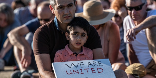 A young boy holds a placard as he takes part in a vigil to remember the victims of the Christchurch mosque attacks, on March 24, 2019, in Christchurch, New Zealand.