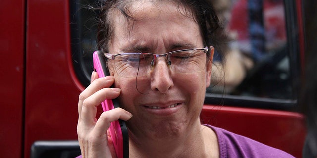 A woman uses her cell phone as she waits for news outside the Raul Brasil State School in Suzano, Sao Paulo state, Brazil.