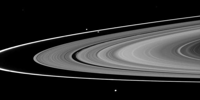 Saturn's moons Prometheus, Pandora and Epimetheus can be seen among the planet's rings in this image from the Cassini spacecraft. New views of Pan, Dasphnis, Atlas, Pandora and Epimetheus have suggested possible reasons for the strange shapes and colors of those moons.