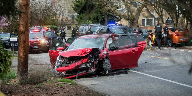 Police work at the scene where two cars collided in Seattle on Wednesday after a gunman opened fire on vehicles in a Seattle neighborhood. (Associated Press)