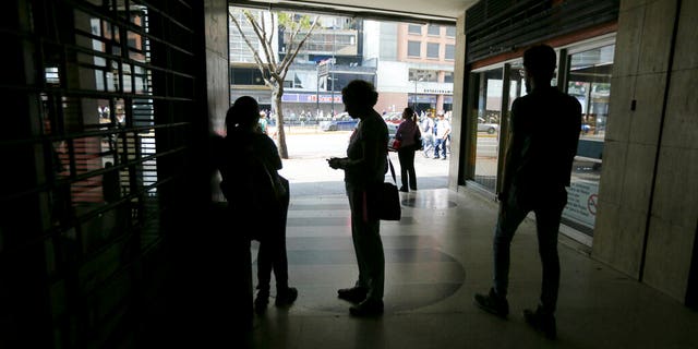 People wait inside a darkened office building during a power outage in Caracas, Venezuela, Monday, March 25, 2019. The subway suspended service because of the power cuts Monday, as local media reported outages in at least six states.