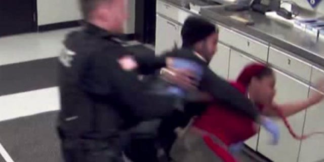 Denisha Davis can be seen struggling with police in a booking room early Sunday.