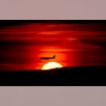 A passenger jet on approach to Newark Liberty International Airport flies over the setting sun in Newark, New Jersey, March 27, 2019.