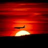 A passenger jet on approach to Newark Liberty International Airport flies over the setting sun in Newark, New Jersey, March 27, 2019.
