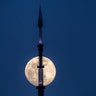 The rising moon passes behind the antenna on top of One World Trade Center in New York City, March 19, 2019.