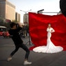 A woman in wedding attire poses for a photo portrait along a busy street in Xi'an in northwestern China's Shaanxi Province, March 28, 2019. 