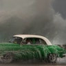 Waves crash against the Malecon sea wall as a taxi drives past in a classic American car in Havana, Cuba, March 19, 2019.