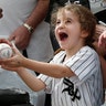 Six-year-old Joan Stiltner, of Chicago, holds a ball for Chicago White Sox left fielder Joel Booker to autograph before the team's spring training baseball game, in Glendale, Ariz., March 7, 2019. 