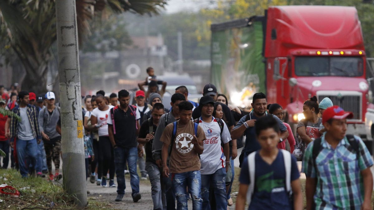 Migrants walk along a highway as a new caravan of several hundred people sets off from San Pedro Sula, Honduras, shortly after dawn on Wednesday, April 10, 2019, in hopes of reaching the distant United States.