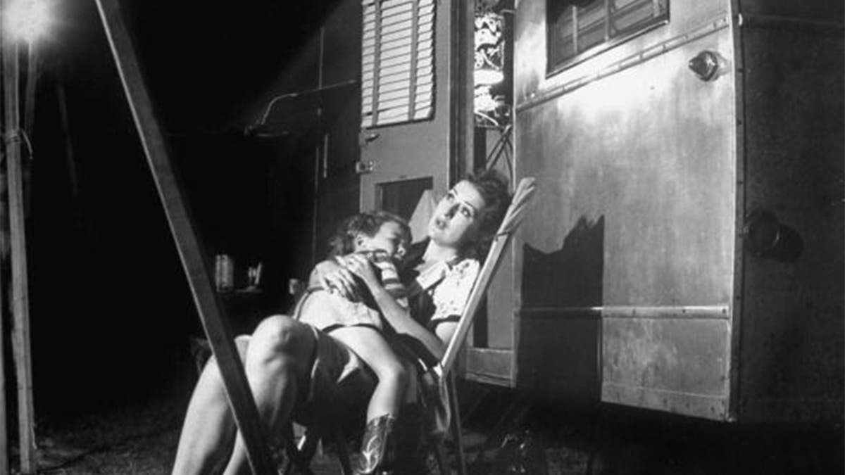 Stripper Gypsy Rose Lee holding her 4-year old son, Erik Lee Kirkland, during a stopover in traveling carnival show.