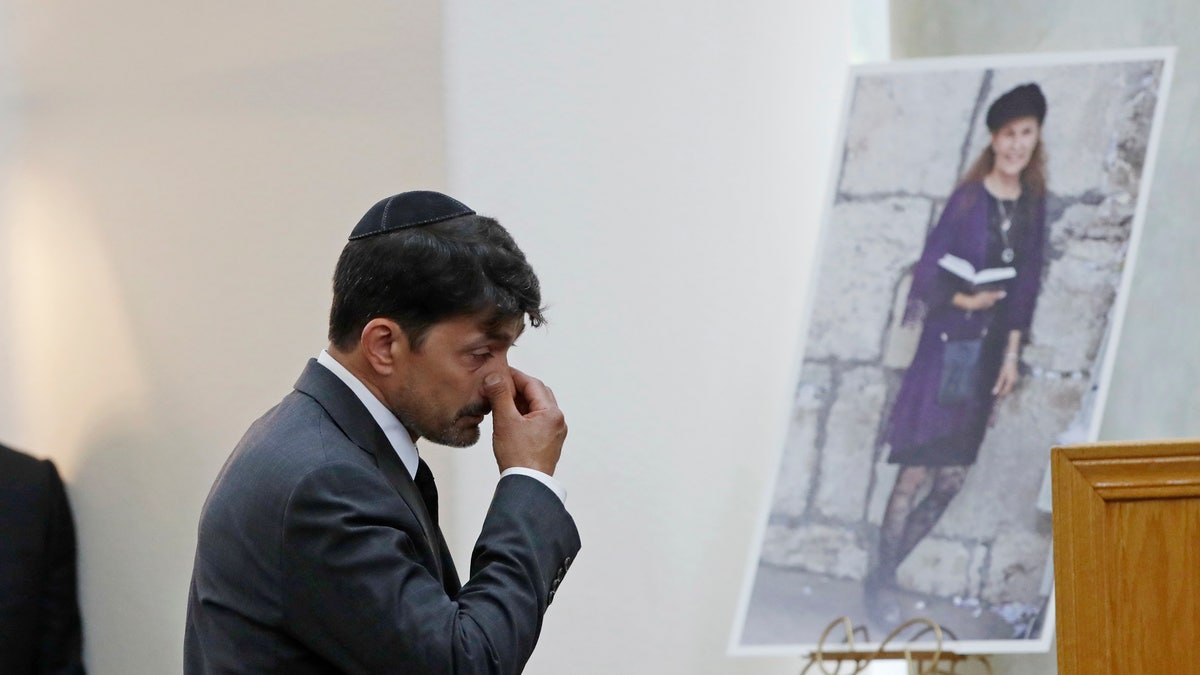 Oscar Stewart, left, walks past a photo of Lori Kaye, Monday, April 29, 2019, as he attends a memorial service for Kaye in Poway, Calif. Stewart was worshipping at the Chabad of Poway synagogue Saturday when a gunman opened fire, killing Kaye. (AP Photo/Gregory Bull)