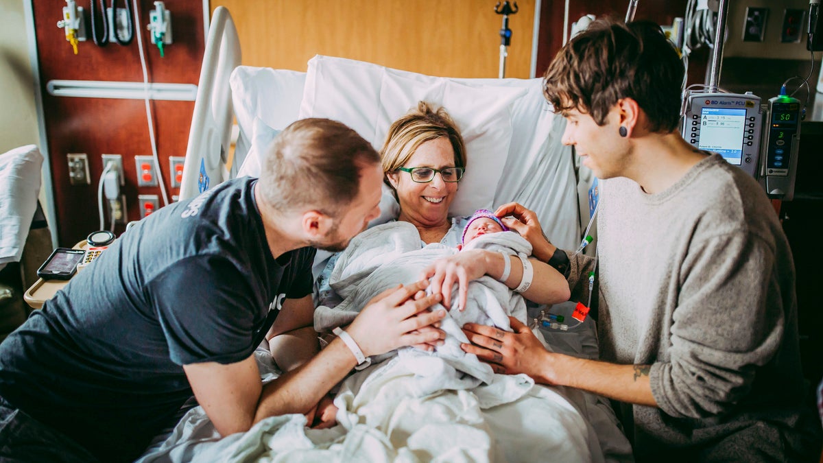 Matthew Eledge, left, his mother Cecile Eledge, center, and Matthew's husband Elliot Dougherty, right, greet baby Uma after her delivery at the Nebraska Medical Center in Omaha, Neb.