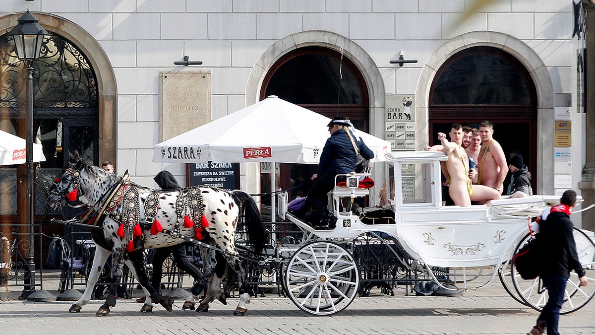 Tourists wearing mankinis travel in a horse cab in Market Square in Krakow, Poland. (AP Photo/Czarek Sokolowski)