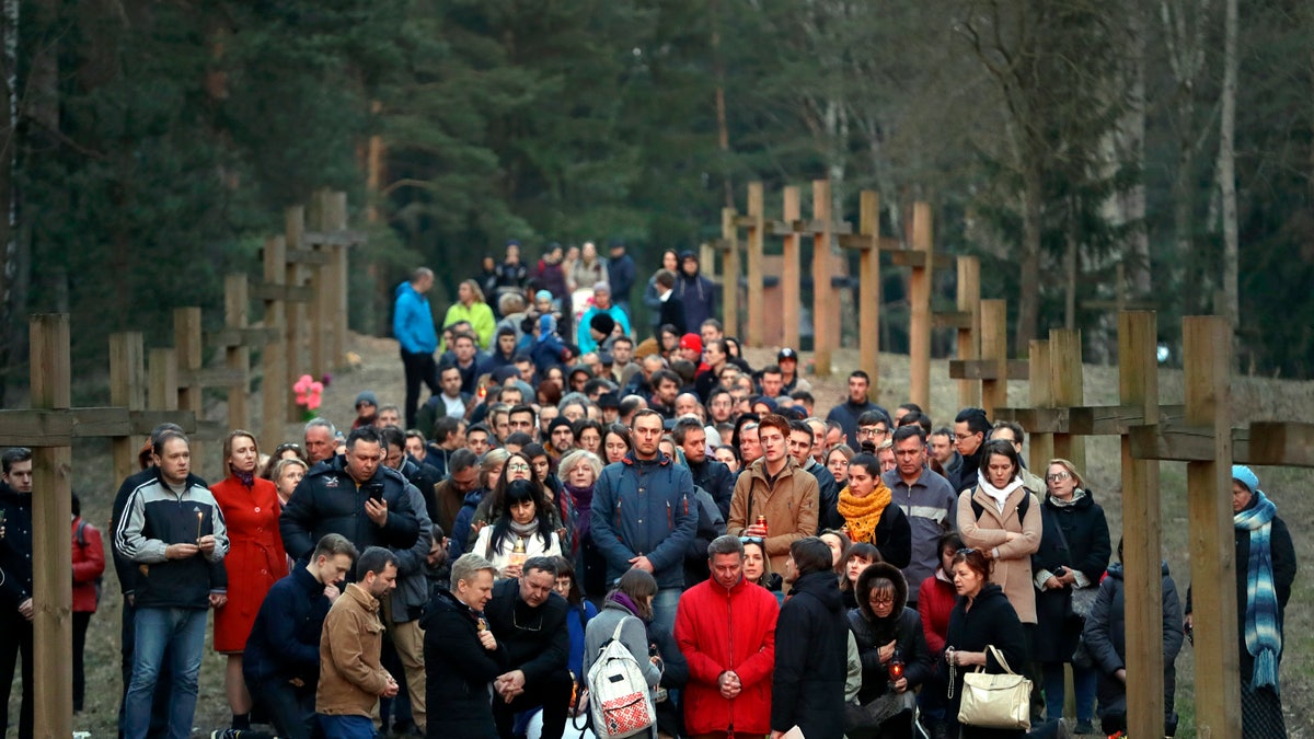 Local residents pray next to the line of wooden crosses marking the Soviet-era mass grave site in Kuropaty, in the Belarus capital Minsk, Thursday, April 4, 2019. Police in Belarus have arrested 15 demonstrators who were trying to prevent the removal of wooden crosses from a wooded area near the capital of Minsk where tens of thousands of people were executed under Soviet dictator Josef Stalin.