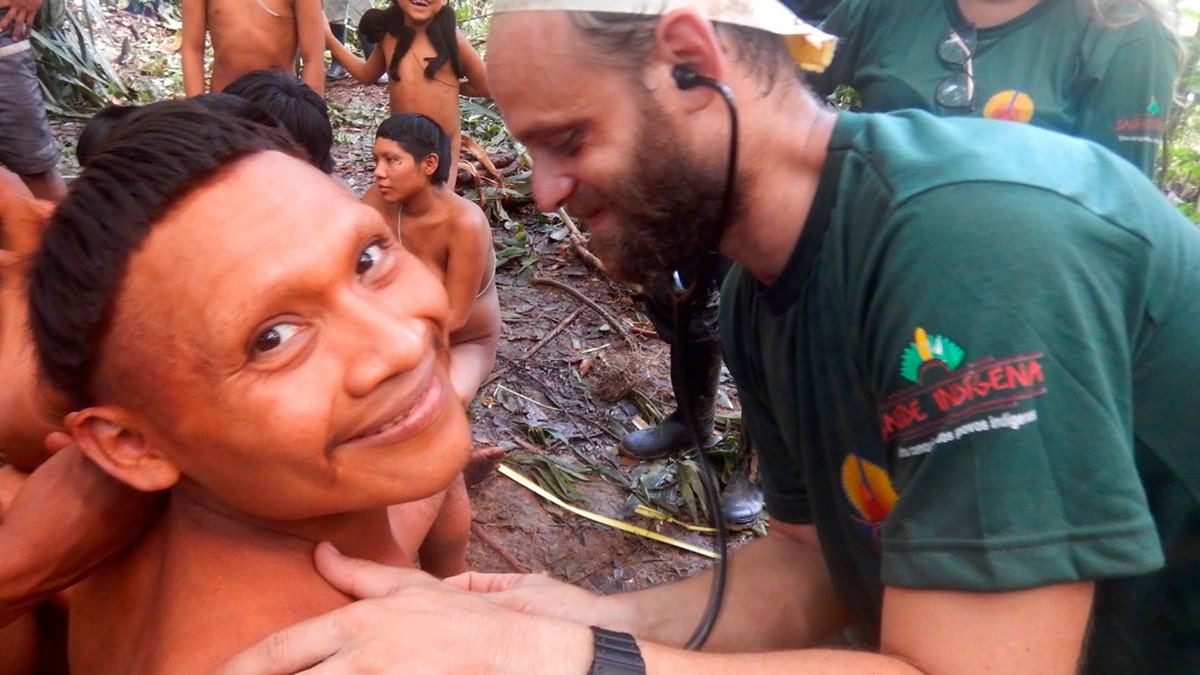 In this 2019 handout photo released by Brazil's National Indian Foundation, or FUNAI, a Korubo man smiled as a FUNAI member checked his heart rate during an expedition to the Javari Valley.
