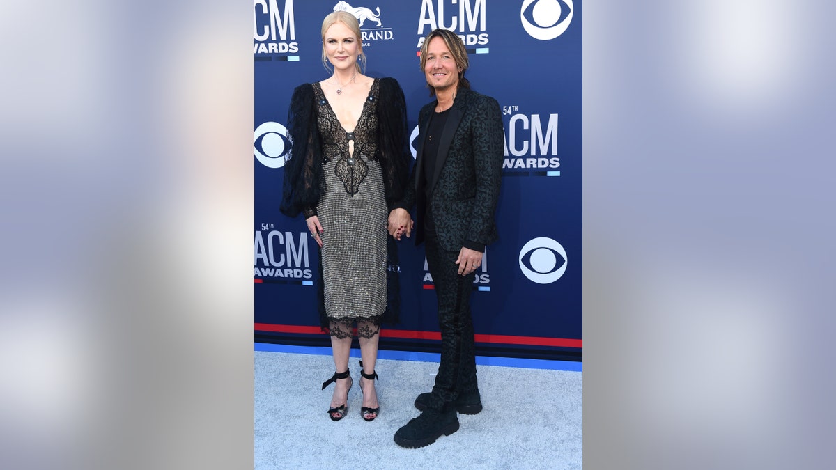 Nicole Kidman, in a shimmery number, and Keith Urban, in an animal print suit, hold hands at the 54th annual Academy of Country Music Awards.