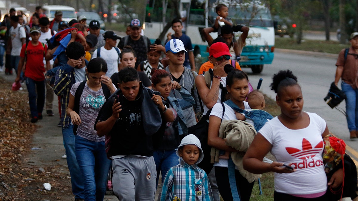 Migrants walk along a highway as a new caravan of several hundred people sets off in hopes of reaching the distant United States, in San Pedro Sula, Honduras, shortly after dawn Wednesday, April 10, 2019. Parents who gathered at the bus station with their children to join the caravan say they can't support their families with what they can earn in Honduras and are seeking better opportunities. (AP Photo/Delmer Martinez)