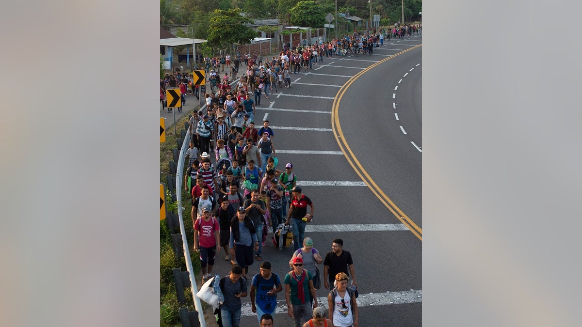 Central American migrants, part of a caravan hoping to reach the U.S. border, walk on the shoulder of a road in Frontera Hidalgo, Mexico on Friday.The group pushed past police guarding the bridge and joined a larger group of about 2,000 migrants who are walking toward Tapachula, the latest caravan to enter Mexico.