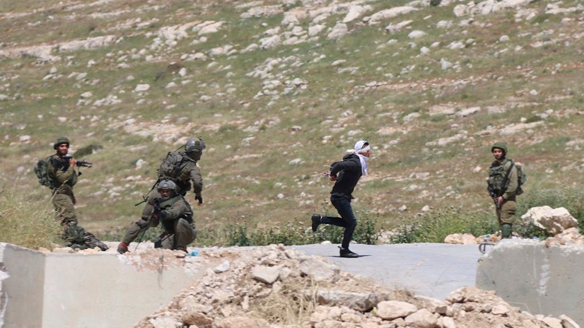 Handcuffed and blindfolded Osama Hajahjeh, 16, runs away from Israeli soldiers near the village of Tekoa, West Bank. Hajahjeh said was shot in his legs last week by Israeli soldiers while he was handcuffed and blindfolded, shortly after being arrested. (AP Photo/Mohammad Hmeid)