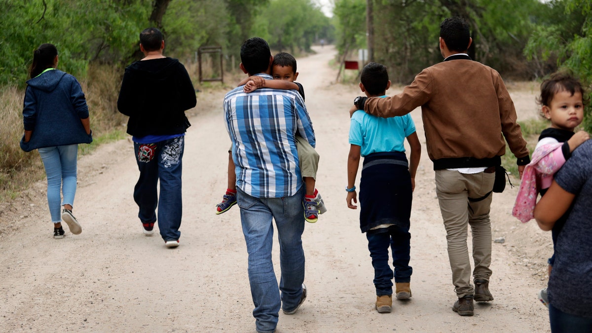 FILE - In this March 14, 2019, file photo, a group of migrant families walk from the Rio Grande, the river separating the U.S. and Mexico in Texas, near McAllen, Texas, right before being apprehended by Border Patrol. U.S. border authorities say they’ve started to increase the biometric data they take from children 13 years of age and younger, including fingerprints, despite privacy concerns and government policy intended to restrict what can be collected from migrant youth. (AP Photo/Eric Gay, File)