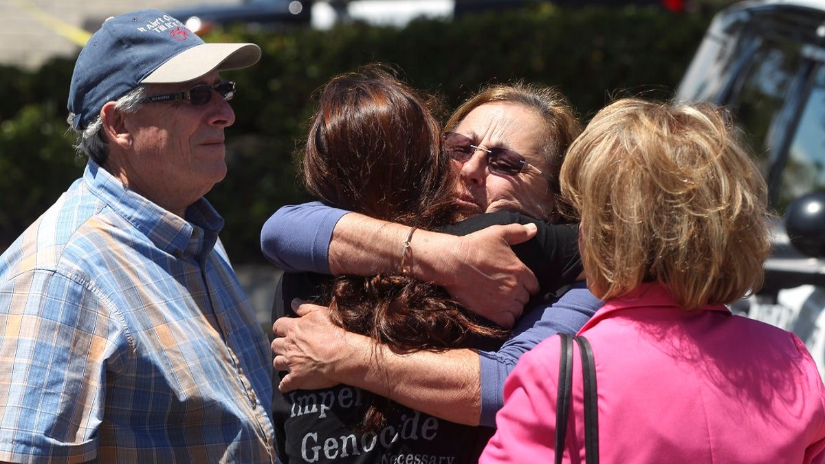 Members of the Chabad synagogue hug as they gather near the Altman Family Chabad Community Center, Saturday in Poway, Calif. (Associated Press)