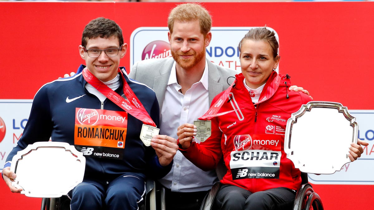 Britain's Prince Harry, center, poses with the men's wheelchair race first place winner Daniel Romanchuk of the United States, left, and women's wheelchair race first place winner Switzerland's Manuela Scharat, right, at the 39th London Marathon in London.