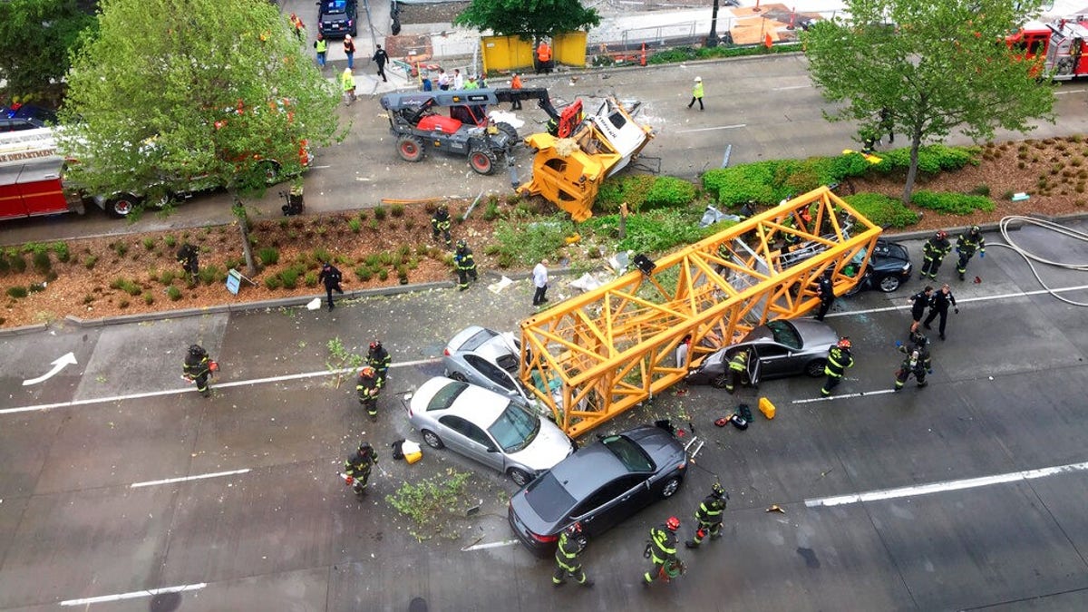 Fire and police crew members work to clear the scene where a construction crane fell from a building on Google's new Seattle campus crashing down onto one of the city's busiest streets and killing multiple people on Saturday.