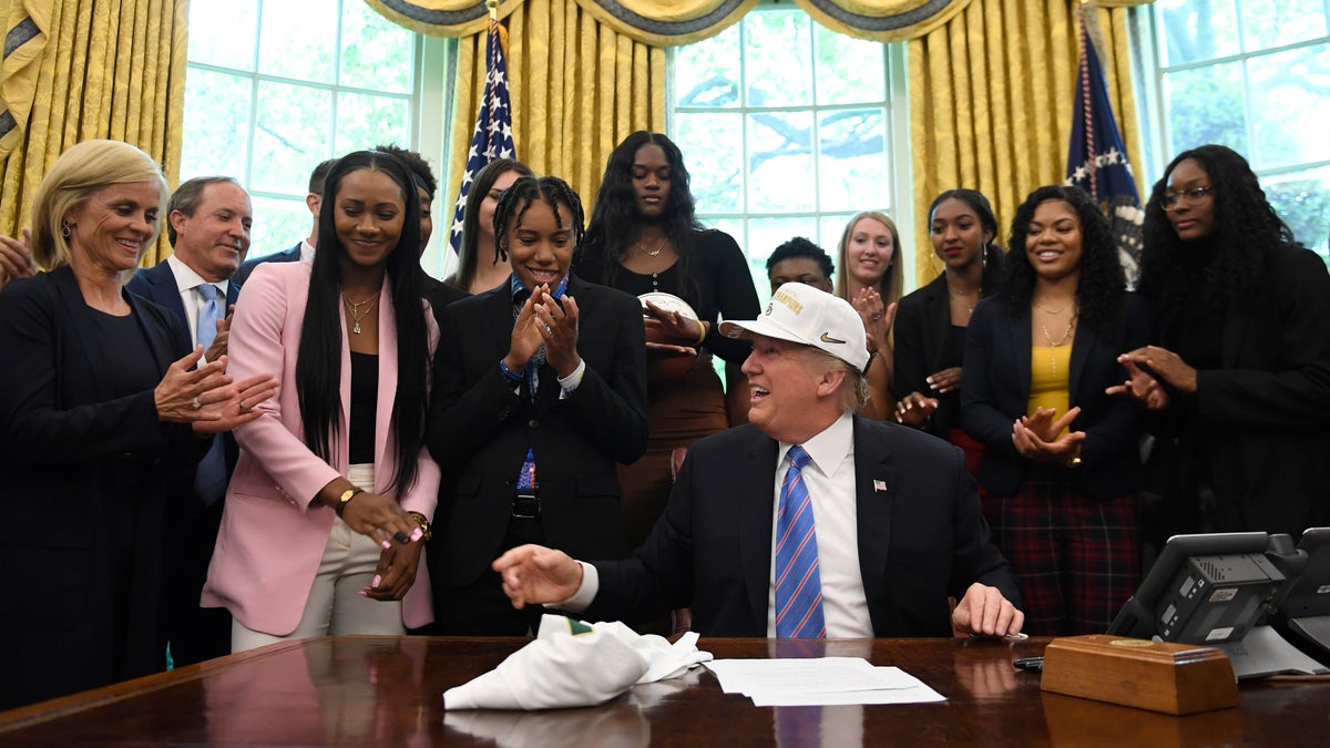 President Donald Trump laughs as he wears a hat that was presented to him as he welcomed members of the Baylor women's basketball team, who are the 2019 NCAA Division I Women's Basketball National Champions, to the Oval Office of the White House in Washington, Monday, April 29, 2019. Baylor women's basketball head coach Kim Mulkey, left, watches. (AP Photo/Susan Walsh)