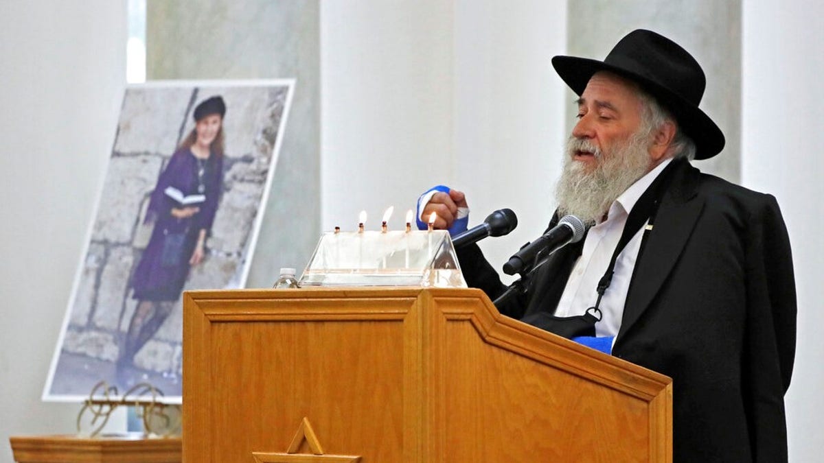 Yisroel Goldstein, Rabbi of Chabad of Poway, speaks Monday during the memorial service for Lori Kaye, who is pictured at left, in Poway, Calif.