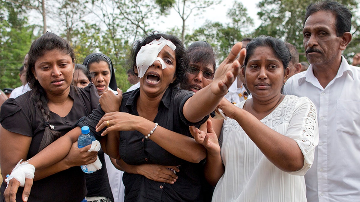 Anusha Kumari, second from left, weeps during a mass burial for her husband, two children and three siblings, all victims of Easter Sunday's bomb attacks, in Negombo, Sri Lanka.