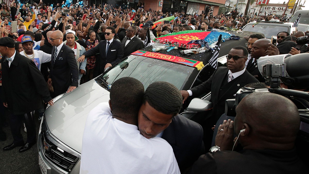 Two men hug as a hearse carrying the casket of slain rapper Nipsey Hussle passes through the crowd Thursday, April 11, 2019, in Los Angeles.(AP Photo/Jae C. Hong)