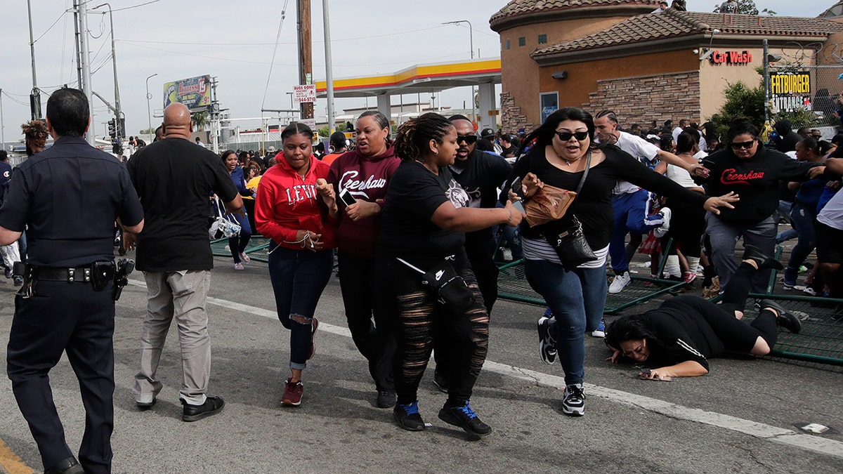 People flee the scene after hearing a loud noise while waiting for a hearse carrying the casket of slain rapper Nipsey Hussle Thursday, April 11, 2019, in Los Angeles. (AP Photo/Jae C. Hong)