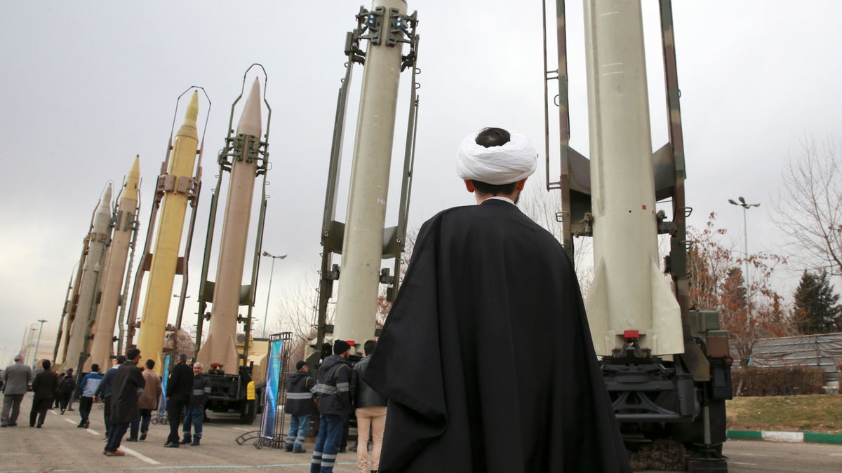 FILE - In this Feb. 3, 2019 file photo, an Iranian clergyman looks at domestically built surface to surface missiles displayed by the Revolutionary Guard in a military show marking the 40th anniversary of the Islamic Revolution, at Imam Khomeini Grand Mosque in Tehran, Iran. On Monday, April 8, 2019, the Trump administration designated Iran’s Revolutionary Guard a “foreign terrorist organization” in an unprecedented move against a national armed force. Iran’s Revolutionary Guard Corps went from being a domestic security force with origins in the 1979 Islamic Revolution to a transnational fighting force. (AP Photo/Vahid Salemi, File)