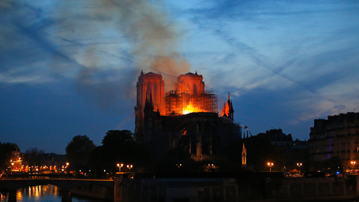 Firefighters tackle the blaze as flames and smoke rises from Notre Dame cathedral as it burns in Paris, Monday, April 15, 2019. Massive plumes of yellow-brown smoke are filling the air above Notre Dame Cathedral and ash is falling on tourists and others around the island that marks the center of Paris. (AP Photo/Michel Euler)