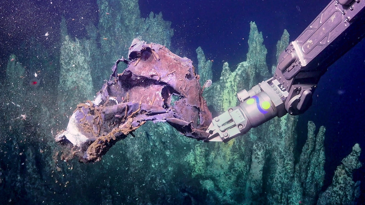 ROV SuBastian picks up some discarded trash near Big Pagoda vent in the Guaymas Basin. (Courtesy of Schmidt Ocean Institute)