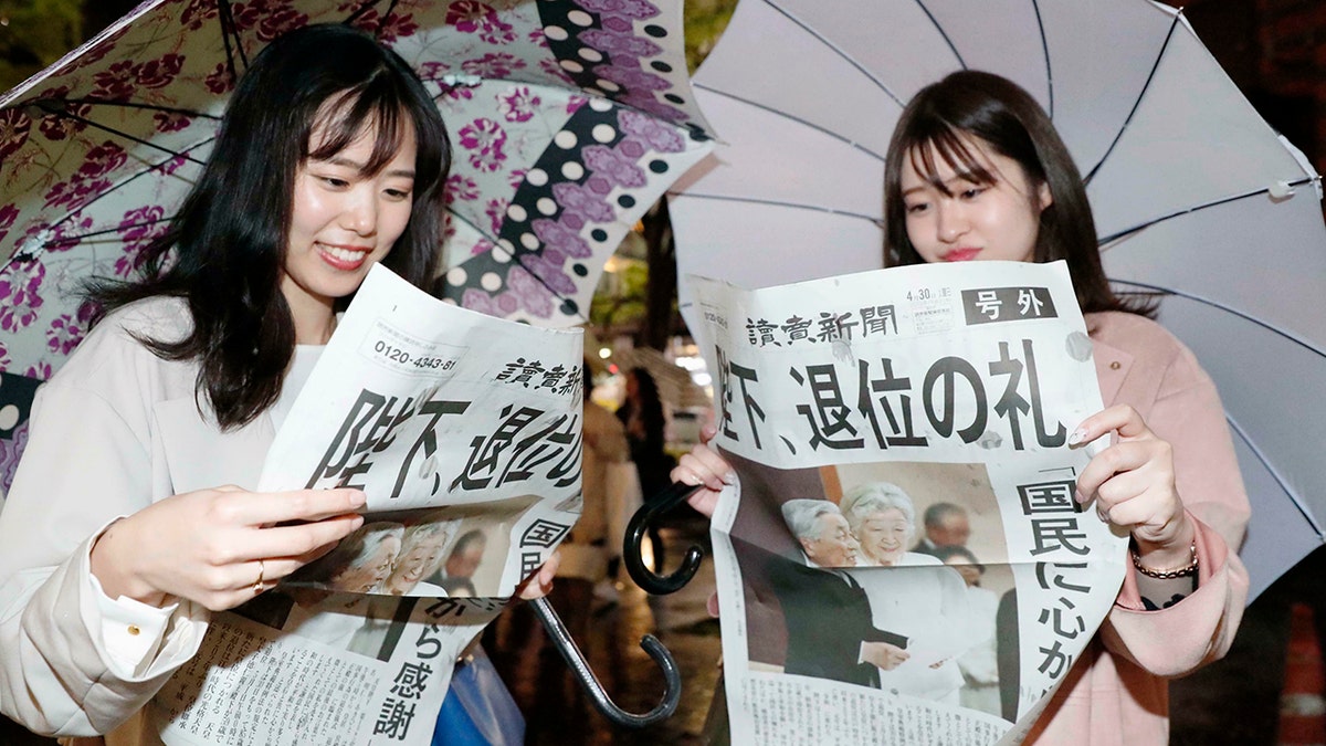 Women read a copy of the extra edition of Yomiuri Shimbun newspaper reporting Emperor Akihito's abdication in Tokyo Tuesday. The headline reads "Emperor, abdication ritual." (Kyodo News via AP)